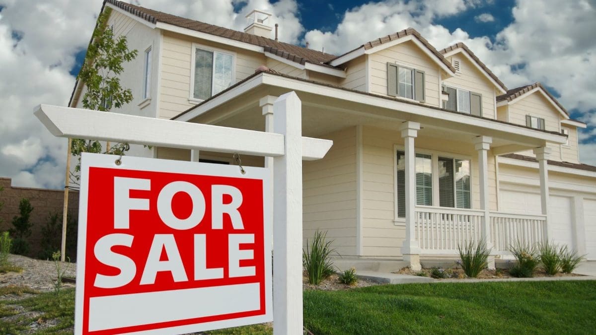 White modern home with a red for sale covering the left side of the picture